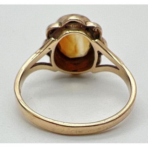 1086 - A 9ct gold citrine set dress ring. An oval cut citrine set in scallop edged mount with rope design d... 