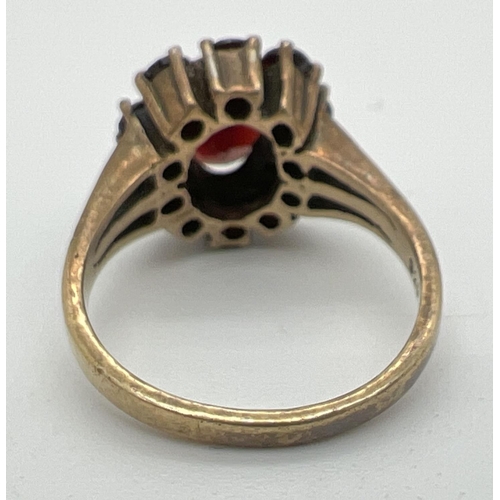 1094 - A vintage silver cocktail style ring set with Garnets. oval cut central garnet surrounded by 10 smal... 