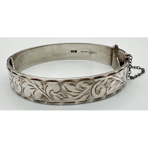 1100 - A vintage silver bangle with full floral engraved decoration and safety chain. Hallmarked Birmingham... 