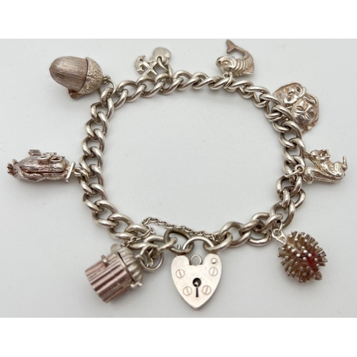 1114 - A vintage silver charm bracelet with padlock and safety chain. Complete with 8 silver and white meta... 