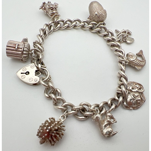 1114 - A vintage silver charm bracelet with padlock and safety chain. Complete with 8 silver and white meta... 