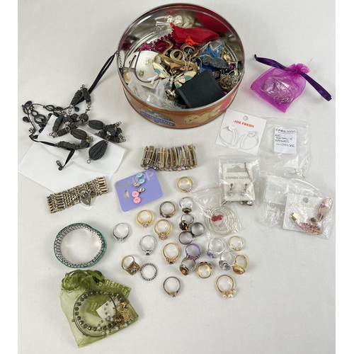 1125 - A tin of modern costume jewellery some with original packaging. To include necklaces, bracelets, rin... 