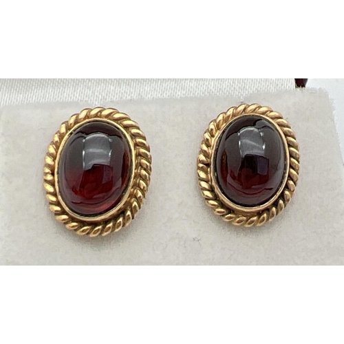 1139 - A pair of gold stud style earrings set with oval cabochon garnets. Rope detail to edges of mounts. N... 