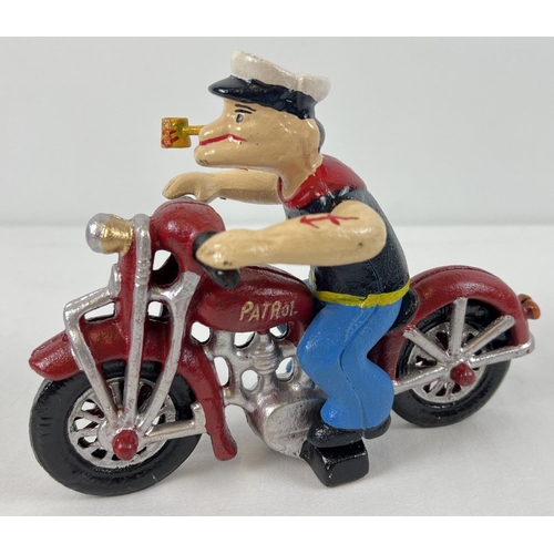 1244 - A painted cast iron figure of Popeye riding a motorcycle. Motorbike has moving wheels and Popeye lif... 