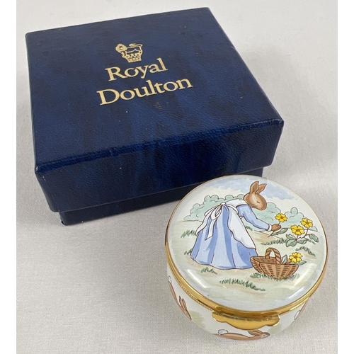 1346 - A boxed Royal Doulton Bunnykins circular enameled trinket box. Depicting a lady rabbit picking flowe... 