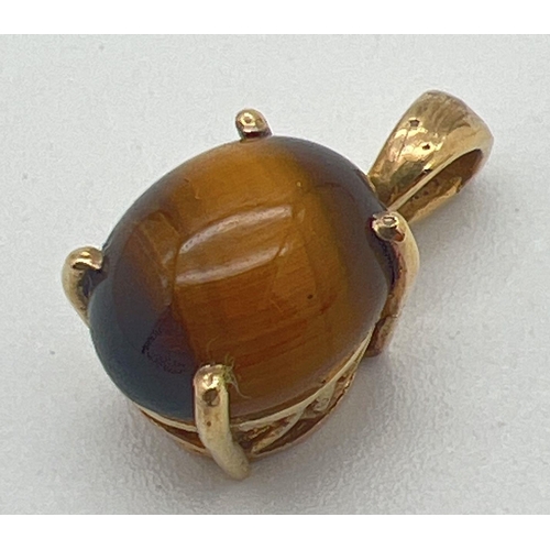 1149 - A gold pierced work mount pendant set with a tigers eye cabochon. Makers mark to back of bale. Tests... 