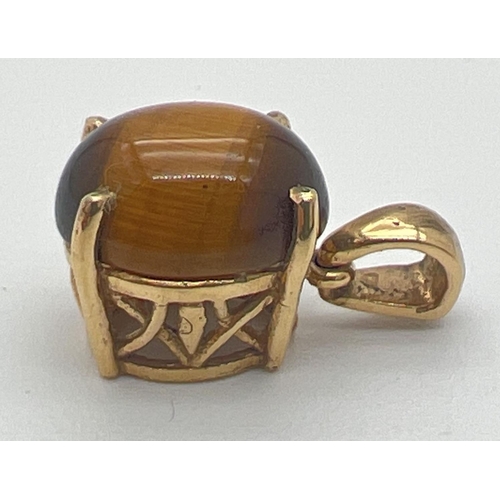 1149 - A gold pierced work mount pendant set with a tigers eye cabochon. Makers mark to back of bale. Tests... 