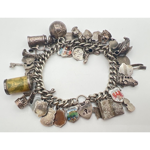 1153 - A vintage silver charm bracelet with padlock, safety chain and 43 silver & white metal charms. Charm... 