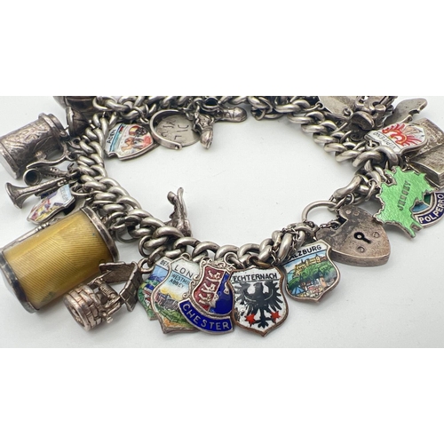 1153 - A vintage silver charm bracelet with padlock, safety chain and 43 silver & white metal charms. Charm... 