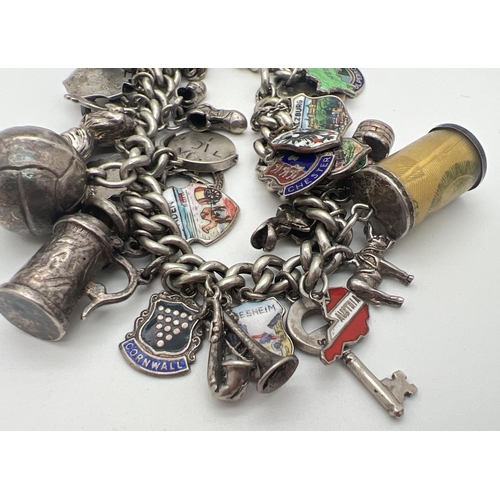 1153 - A vintage silver charm bracelet with padlock, safety chain and 43 silver & white metal charms. Charm... 