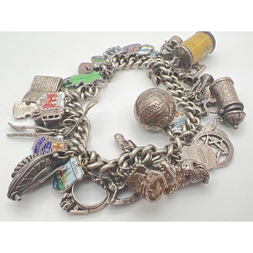 1153 - A vintage silver charm bracelet with padlock, safety chain and 43 silver & white metal charms. Charm... 