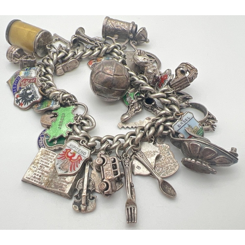 1153 - A vintage silver charm bracelet with padlock, safety chain and 43 silver & white metal charms. Charm... 