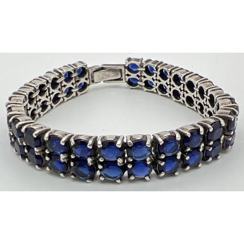 1169 - A double row tennis style silver bracelet set with oval cut dark blue glass stones. Approx 7.5 inche... 