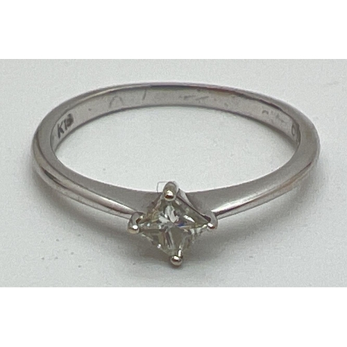 1176 - A 18ct white gold diamond solitaire ring. Plain band set with a 0.10ct square cut diamond. Gold mark... 