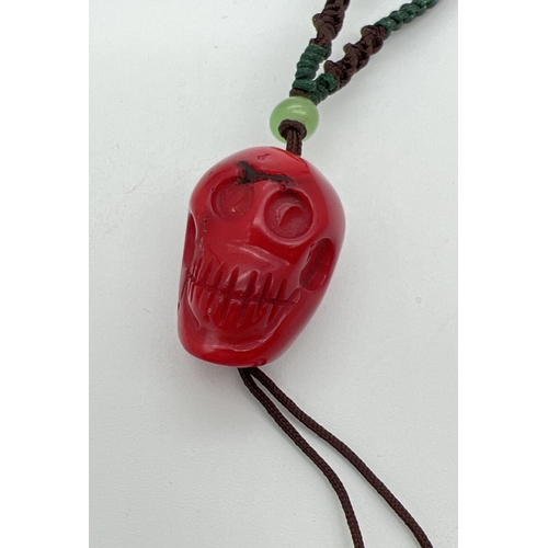 1181 - A carved coral bead in the form of a skull, on a twisted cord thong necklace. Cord is length adjusti... 