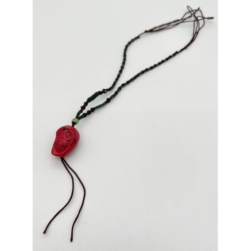 1181 - A carved coral bead in the form of a skull, on a twisted cord thong necklace. Cord is length adjusti... 