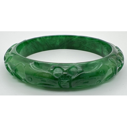 1182 - A Chinese green jade bangle with carved flower & butterfly design. Approx. 7.5cm diameter.