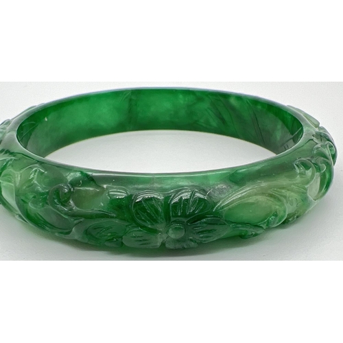 1182 - A Chinese green jade bangle with carved flower & butterfly design. Approx. 7.5cm diameter.