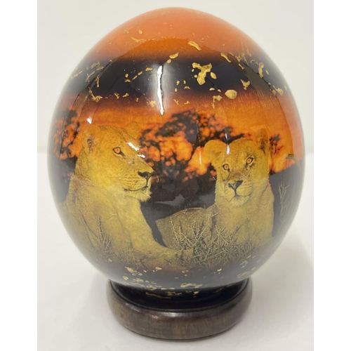 1370 - A painted and lacquered African Ostrich egg with lions at sunset scene and gold fleck detail with a ... 