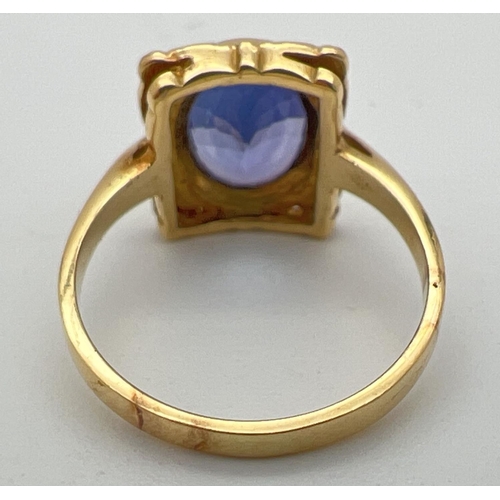 1 - An 18ct yellow gold and tanzanite ring with a decorative square shaped mount. Large oval cut tanzani... 