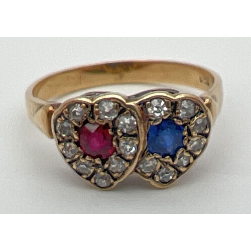13 - An 18ct gold, ruby, sapphire and diamond ring in a double heart shaped setting. Central round cut ru... 