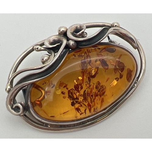 15 - A silver and cognac Baltic amber brooch pendant of Art Nouveau design. With decorative swirl detail ... 