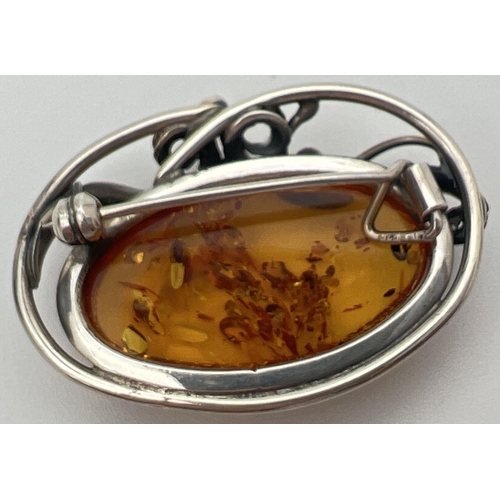 15 - A silver and cognac Baltic amber brooch pendant of Art Nouveau design. With decorative swirl detail ... 