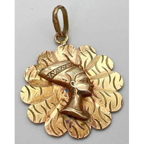 19 - An 18ct yellow gold flower shaped pendant featuring Nefertiti. Bale stamped 750 and pendant tests as... 