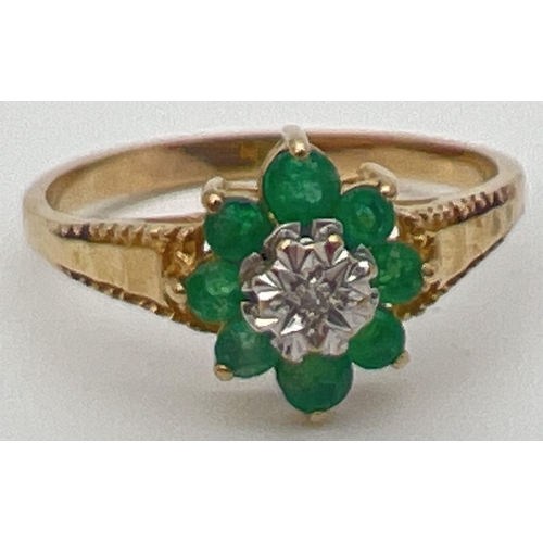 23 - An unmarked 9ct gold, emerald and diamond ring in a flower shaped setting with decorative shoulders.... 