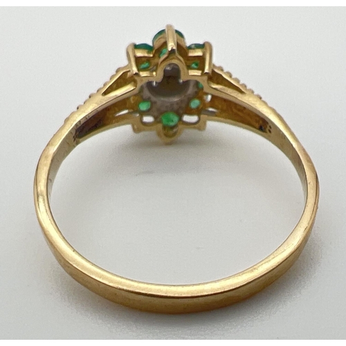 23 - An unmarked 9ct gold, emerald and diamond ring in a flower shaped setting with decorative shoulders.... 