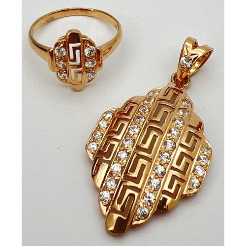 31 - A 21ct gold plated pendant and matching ring set with clear stones. Both with pierced work Greek key... 