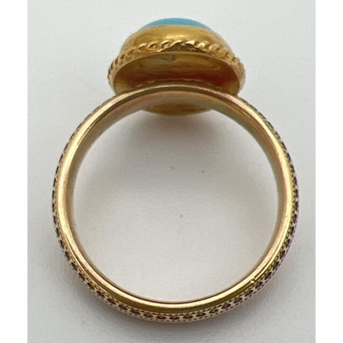 34 - A 9ct gold dress ring set with an oval cabochon of turquoise. Band of ring has studded engraved deta... 