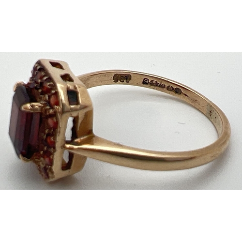 38 - A 9ct gold and garnet dress ring with central emerald cut stone in a basket style setting. Surrounde... 