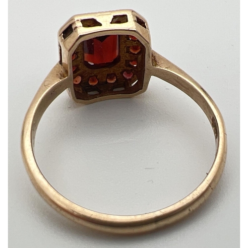 38 - A 9ct gold and garnet dress ring with central emerald cut stone in a basket style setting. Surrounde... 