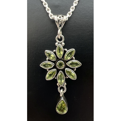 50 - A silver and peridot flower design pendant on an 18