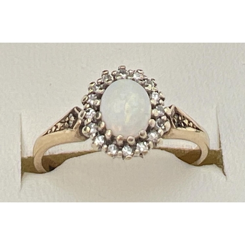 74 - A 9ct gold, opal and diamond dress ring set with central oval cabochon of opal. Surrounded by a halo... 