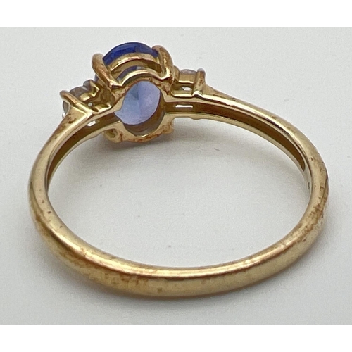 76 - A 10k yellow gold dress ring set with central oval tanzanite between 2 round cut white spinels. Full... 