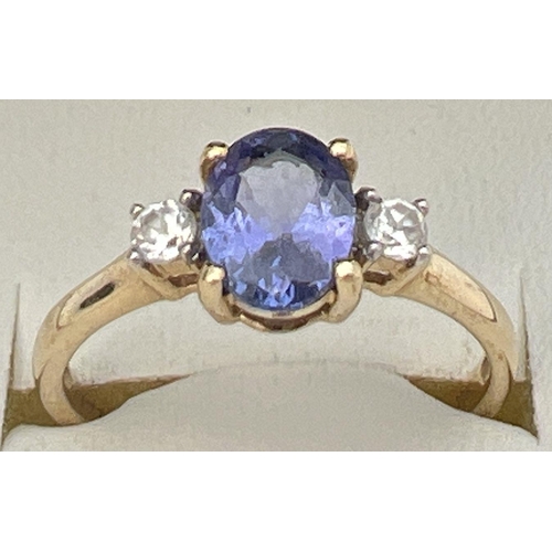 76 - A 10k yellow gold dress ring set with central oval tanzanite between 2 round cut white spinels. Full... 