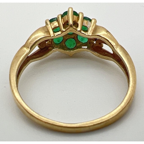 83 - A 9ct gold & emerald cluster ring set with 2 small diamonds on decorative pierced work shoulders. A ... 