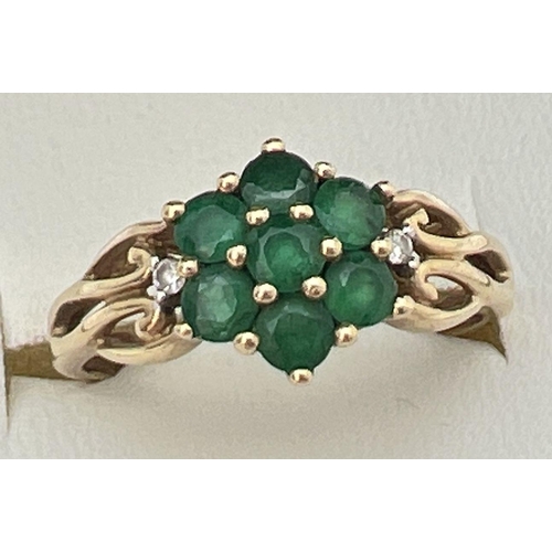 83 - A 9ct gold & emerald cluster ring set with 2 small diamonds on decorative pierced work shoulders. A ... 