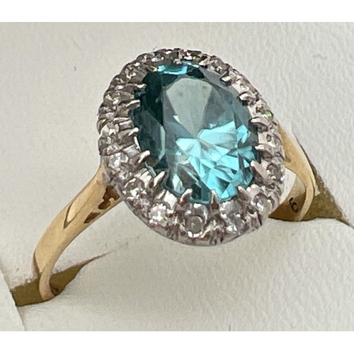 97 - An 18ct gold halo set London blue topaz and diamond dress ring. Large oval cut central topaz stone, ... 