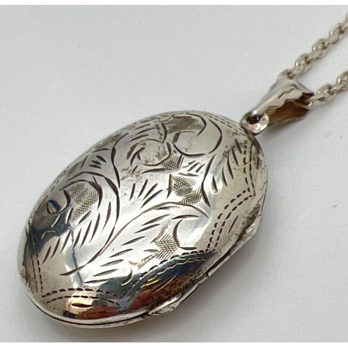 124 - A large silver oval shaped locket on an 18