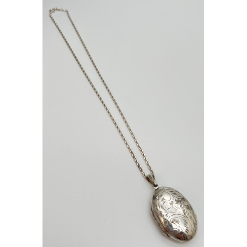 124 - A large silver oval shaped locket on an 18