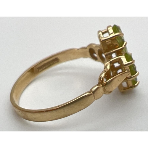 126 - A 9ct gold and peridot ring in a quatrefoil shaped setting with shaped shoulders. 4 oval cut peridot... 