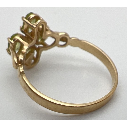 126 - A 9ct gold and peridot ring in a quatrefoil shaped setting with shaped shoulders. 4 oval cut peridot... 