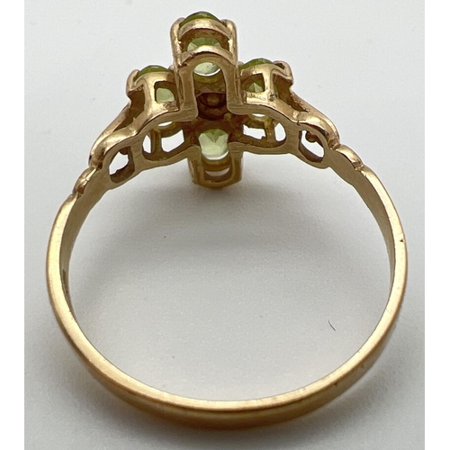 126 - A 9ct gold and peridot ring in a quatrefoil shaped setting with shaped shoulders. 4 oval cut peridot... 