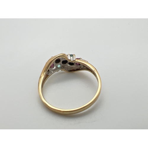 127 - A 9ct gold ring with a twisted design mount, set with rubies, sapphires, emeralds & diamonds. Fully ... 