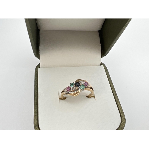 127 - A 9ct gold ring with a twisted design mount, set with rubies, sapphires, emeralds & diamonds. Fully ... 