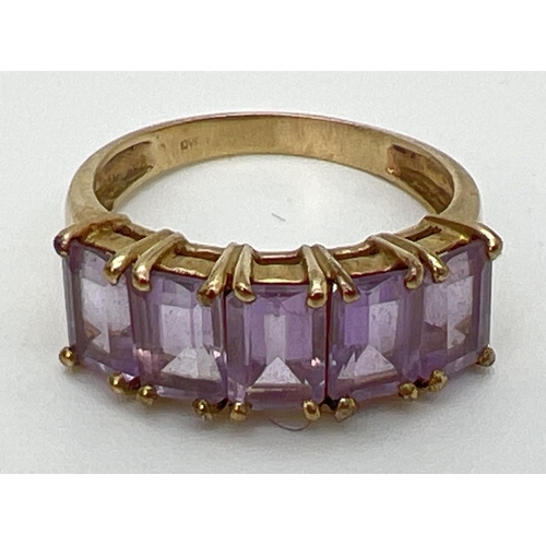 131 - A 9ct gold eternity style ring set with 5 large baguette cut amethyst stones. Each measuring approx.... 