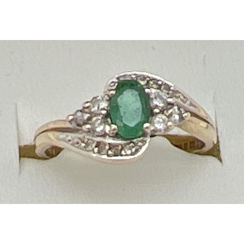 141 - A 9ct gold, emerald and diamond ring with a modern twist design setting. Central oval cut emerald wi... 